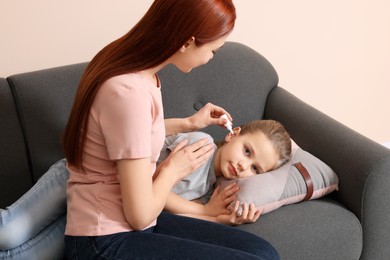 Mother dripping medication into daughter's ear in living room