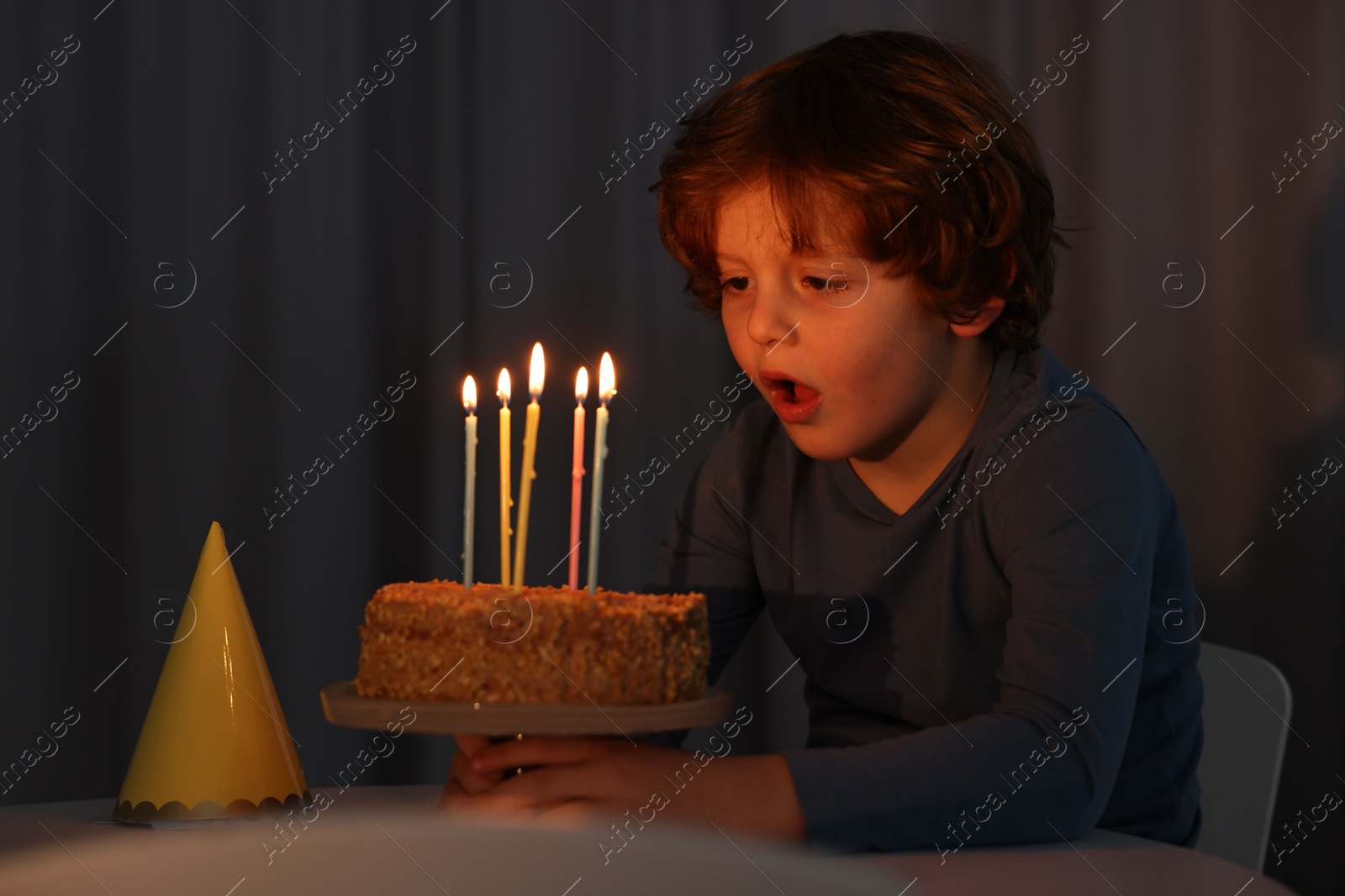 Photo of Cute boy with birthday cake at table indoors