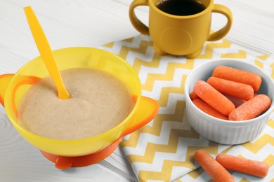 Baby food. Puree in bowl, small carrots and drink on white wooden table