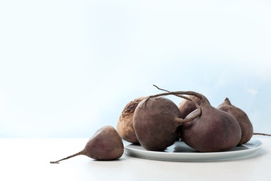Photo of Plate with ripe raw beets on table