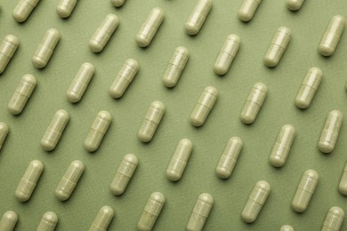 Vitamin capsules on olive background, flat lay