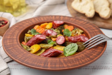Photo of Delicious sausage with baked vegetables and fork on table background, closeup