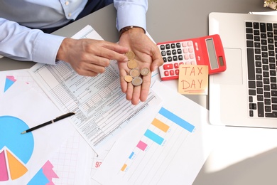 Photo of Tax accountant with money and documents at table