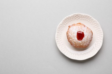 Photo of Hanukkah donut with jelly and powdered sugar on light grey background, top view. Space for text