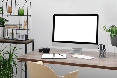 Comfortable workplace at home. Modern computer with blank screen and stationery on wooden desk. Mockup for design