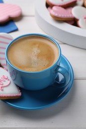 Photo of Delicious heart shaped cookies and cup of coffee on white wooden table