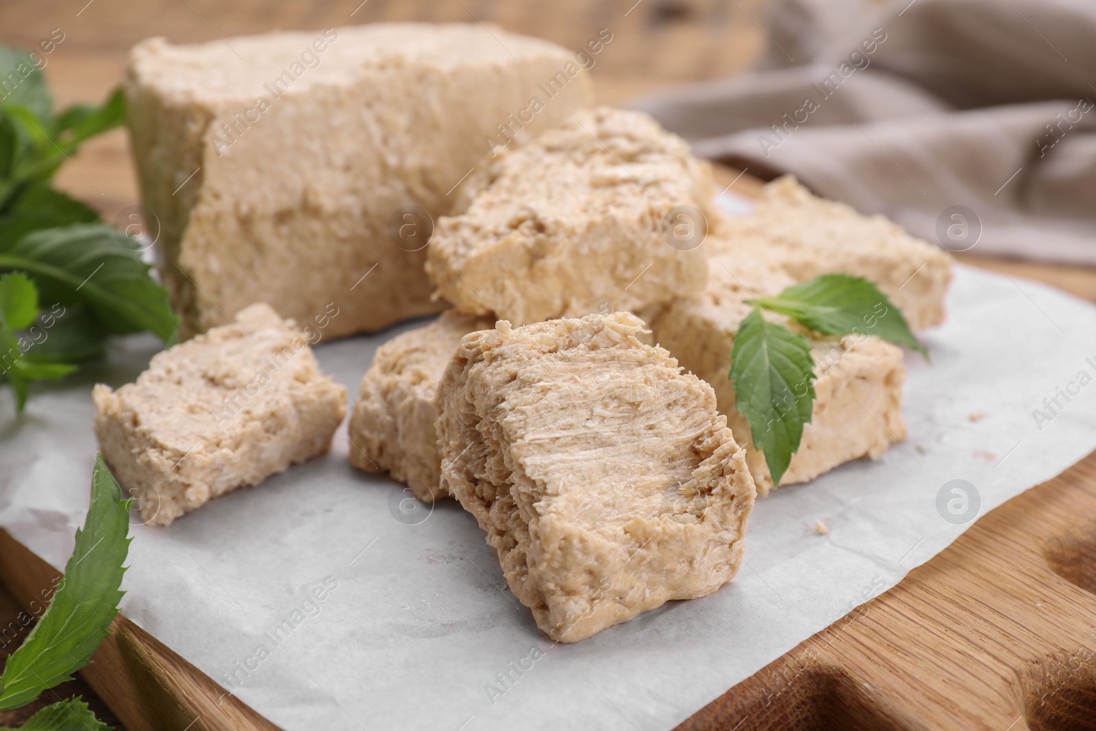 Photo of Pieces of tasty halva and mint leaves on table, closeup