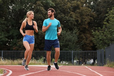 Photo of Healthy lifestyle. Happy sporty couple running at stadium, space for text