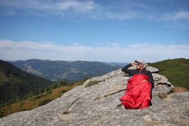 Tourist in sleeping bag on mountain peak