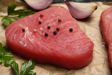 Photo of Raw tuna fillet with parsley and spices on parchment paper, closeup