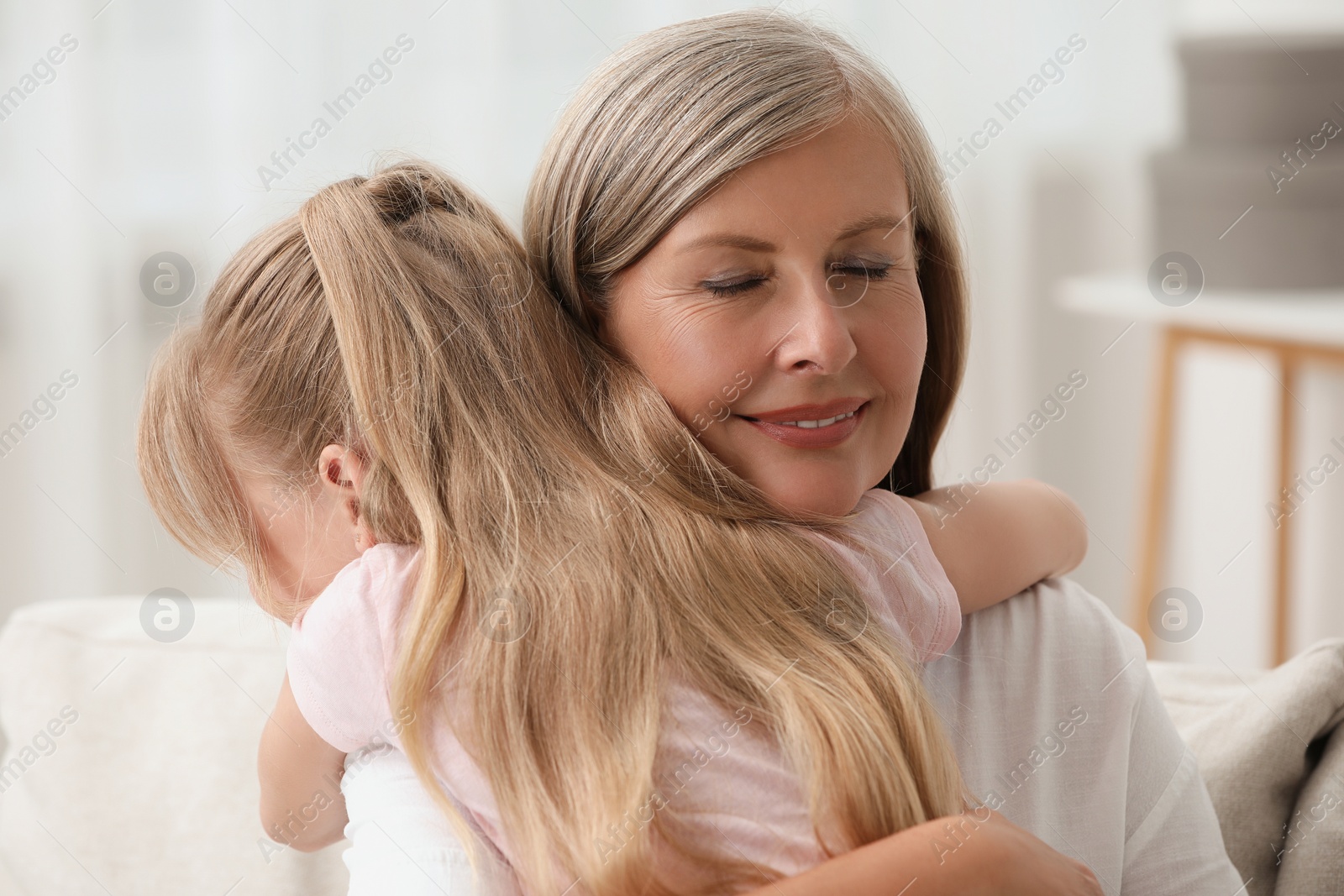 Photo of Happy grandmother hugging her granddaughter at home