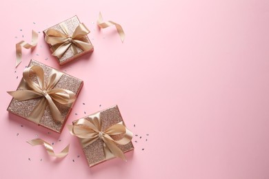 Photo of Three gift boxes and confetti on pink background, flat lay. Space for text
