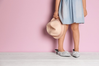 Photo of Little girl in oversized shoes near color wall with space for text, closeup on legs