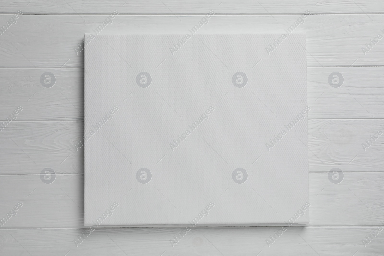 Photo of Blank canvas on white wooden background, space for text