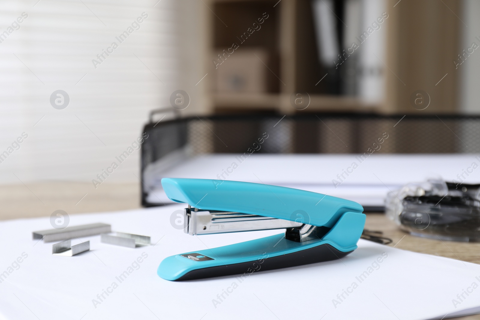 Photo of Stapler, paper and metal staples on table indoors, closeup