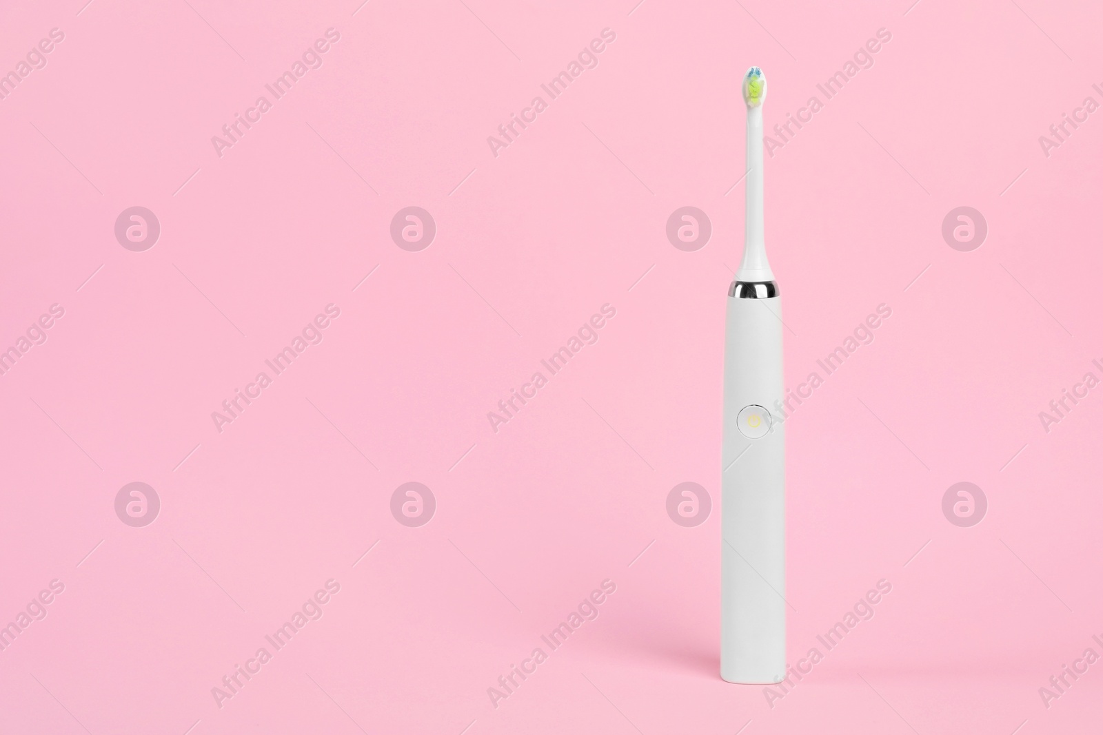 Photo of Electric toothbrush on pink background, space for text