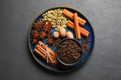 Dishware with different spices and nuts on gray table, top view