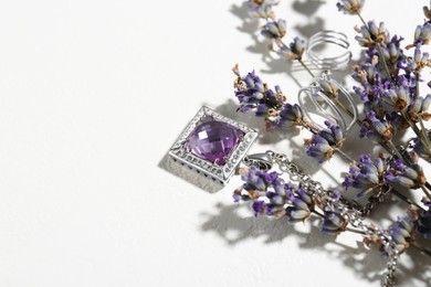 Photo of Beautiful jewelry and lavender flowers on white table, space for text