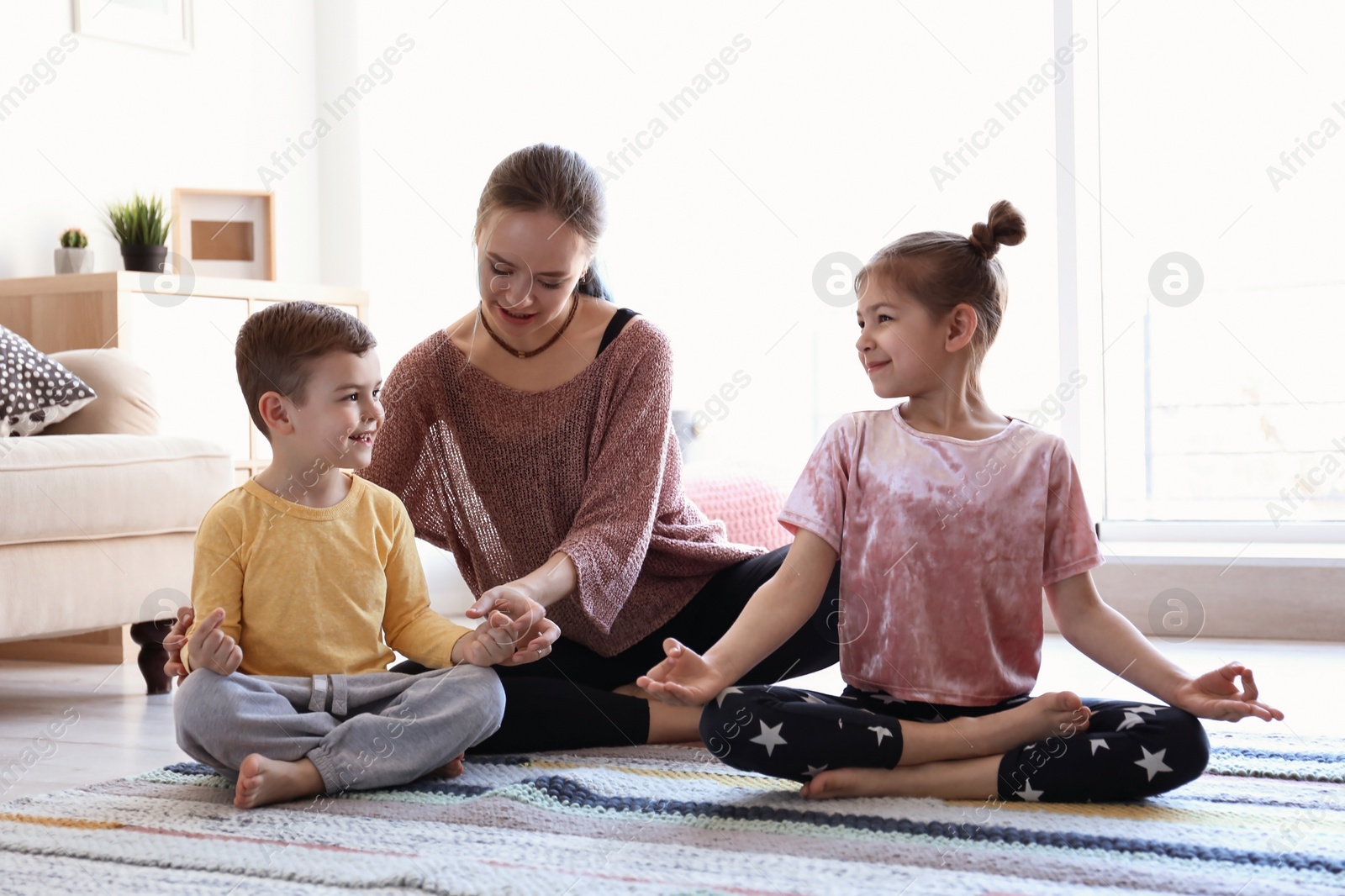 Photo of Young mother and her children practicing yoga at home