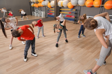 Photo of Cute little children and trainer doing physical exercise in school gym. Healthy lifestyle