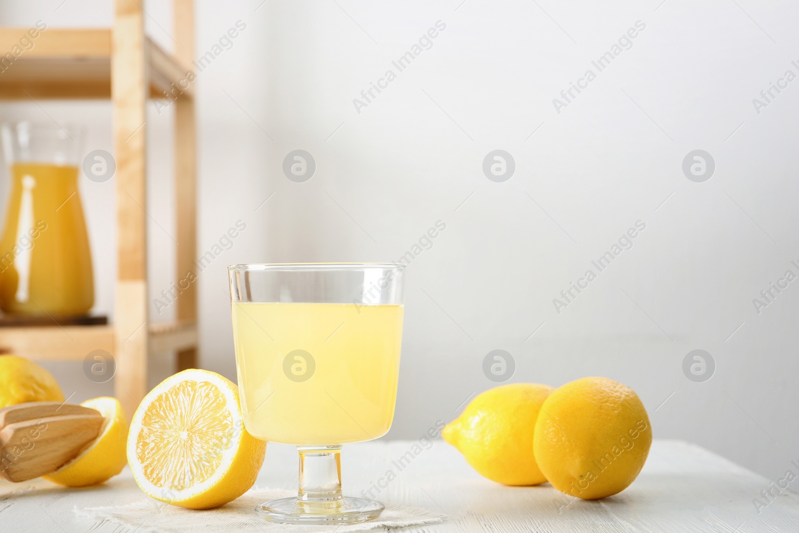 Photo of Glass with fresh lemon juice and fruits on table