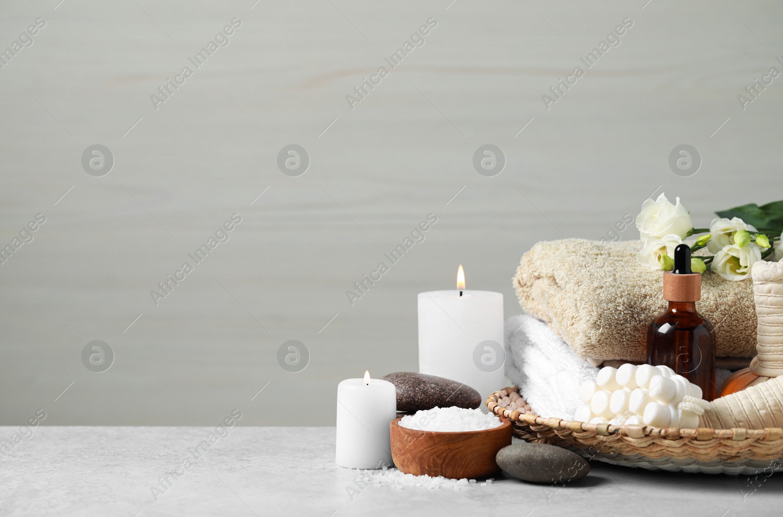 Photo of Beautiful composition with burning candles and different spa products on light grey table. Space for text