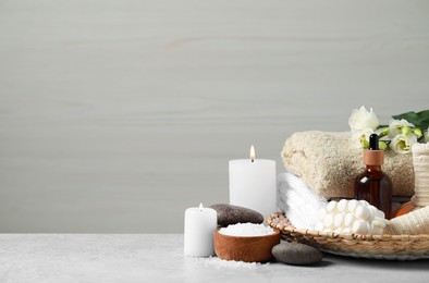 Photo of Beautiful composition with burning candles and different spa products on light grey table. Space for text