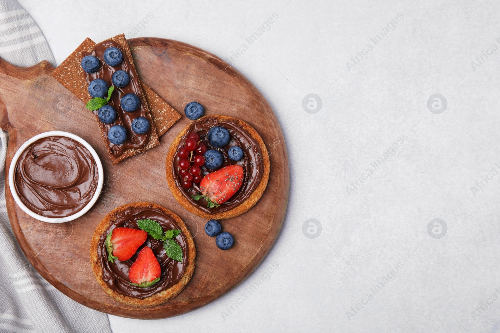 Photo of Fresh rye crispbreads and rusks with different toppings on light grey table, top view. Space for text