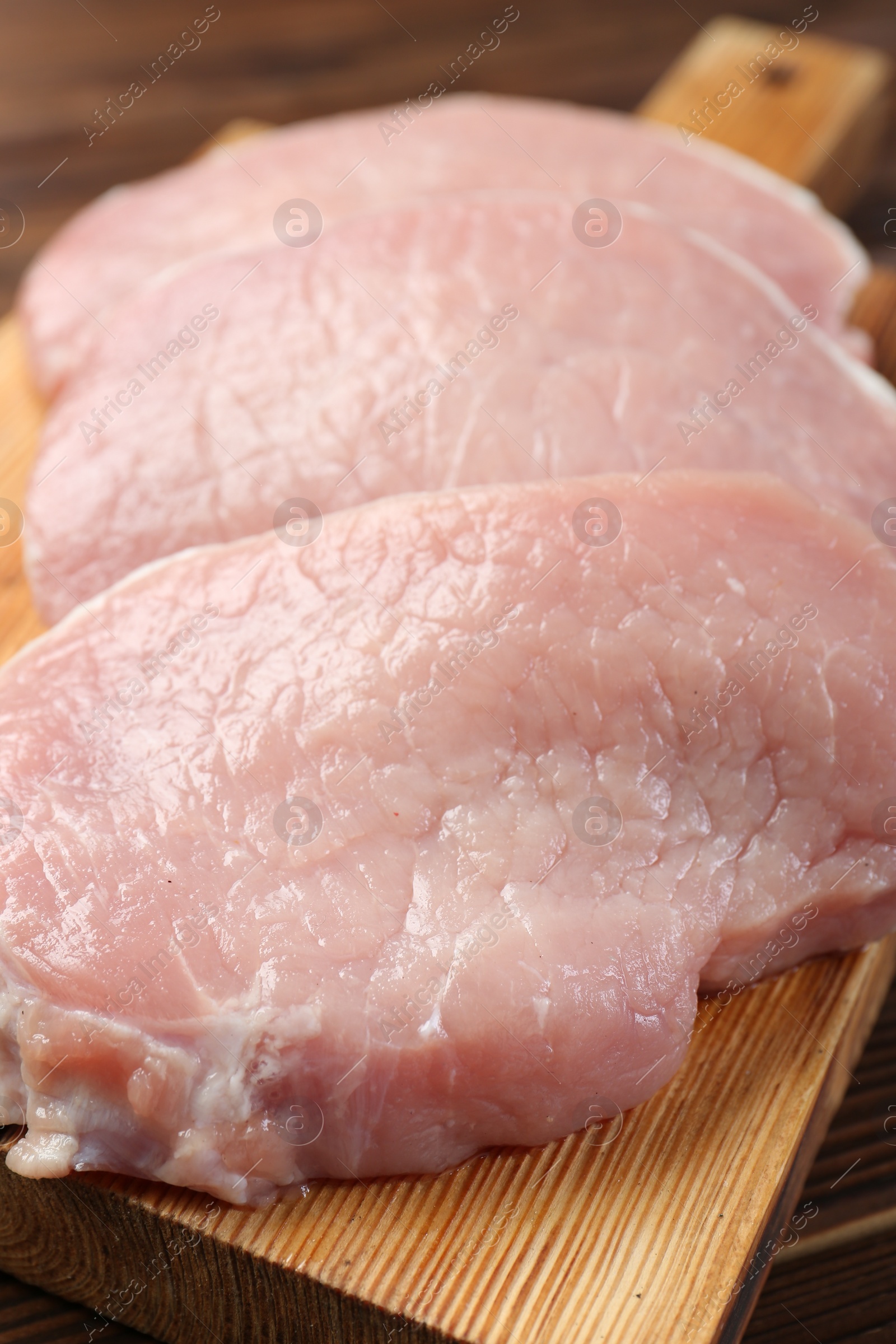 Photo of Pieces of raw pork meat on wooden table, closeup