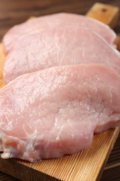 Photo of Pieces of raw pork meat on wooden table, closeup