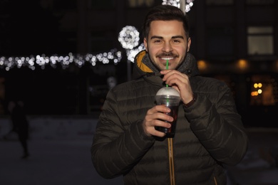 Photo of Man with cup of mulled wine at winter fair