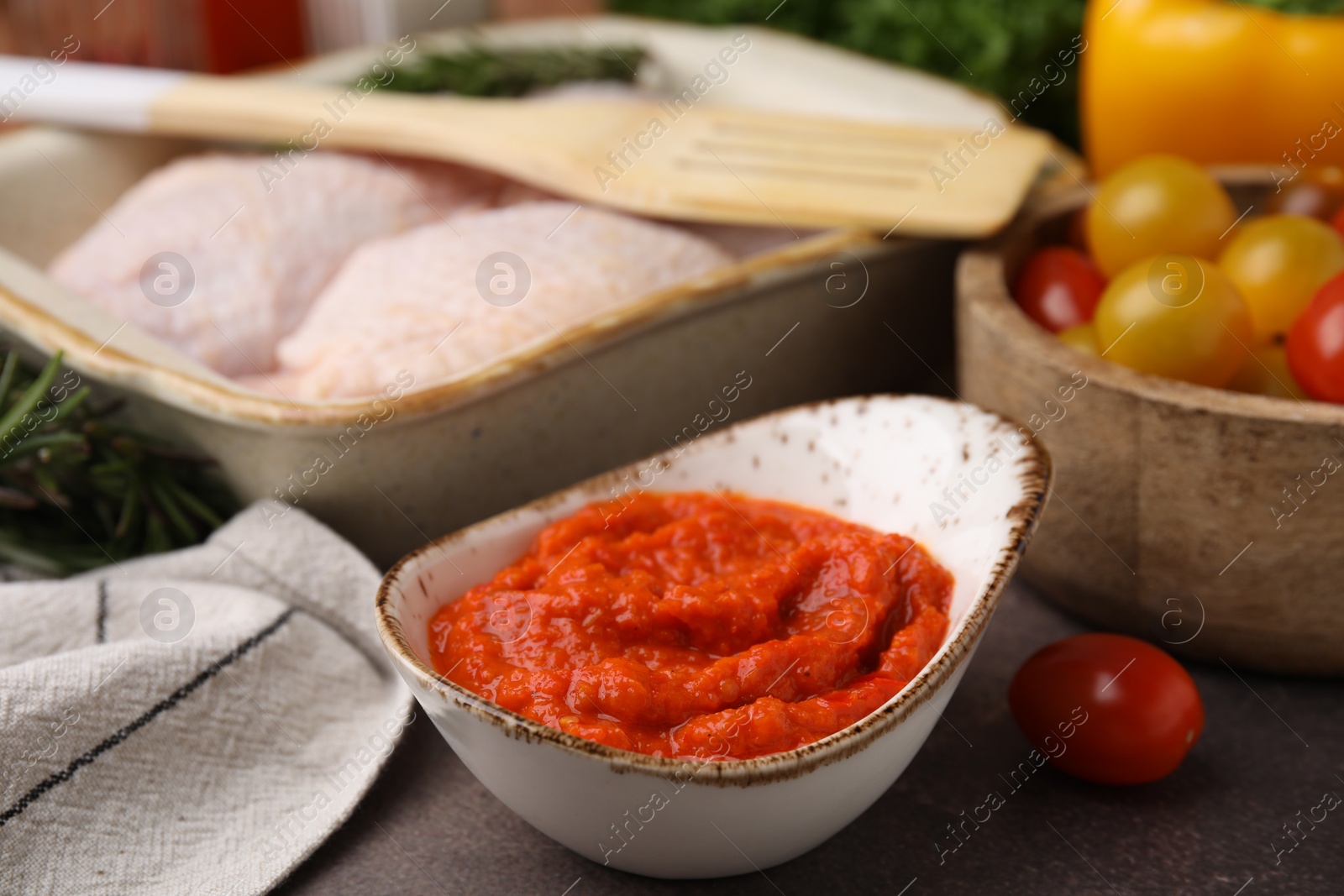 Photo of Fresh marinade, raw chicken and tomatoes on brown table, closeup