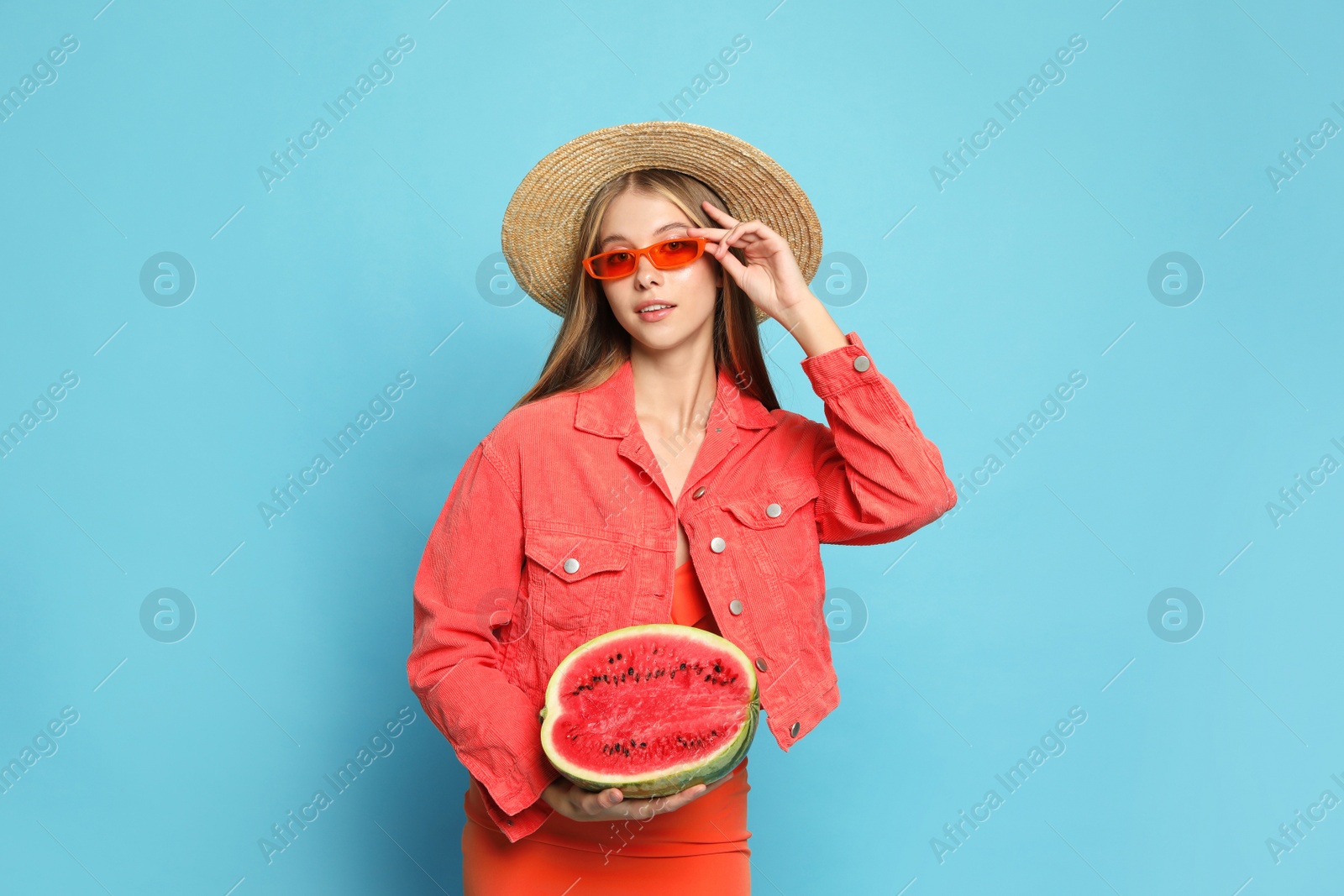 Photo of Beautiful girl with half of watermelon on light blue background