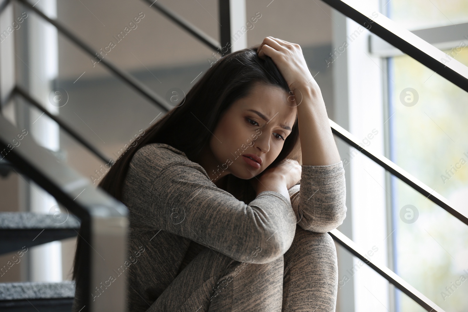 Photo of Depressed young woman sitting on stairs