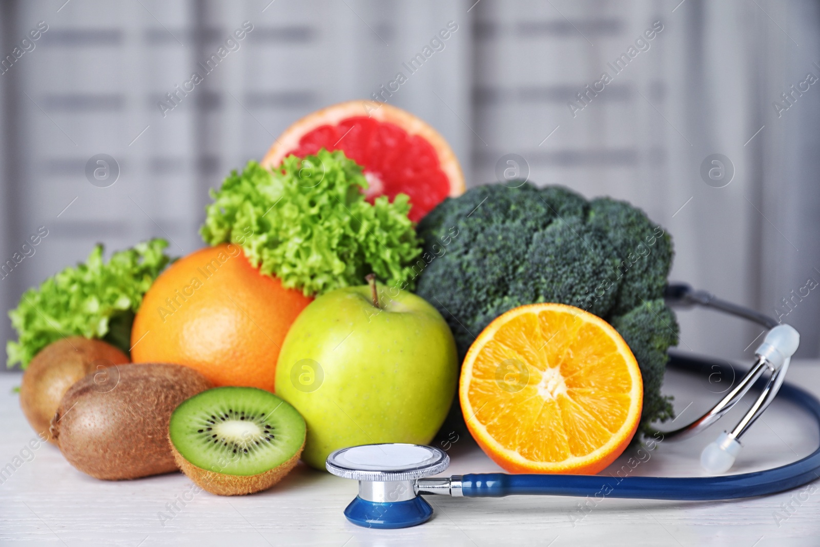 Photo of Stethoscope, vegetables and fruits on white table. Diet plan from nutritionist