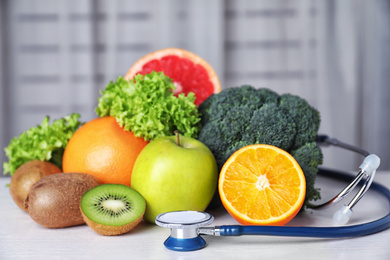 Photo of Stethoscope, vegetables and fruits on white table. Diet plan from nutritionist