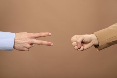 People playing rock, paper and scissors on brown background, closeup