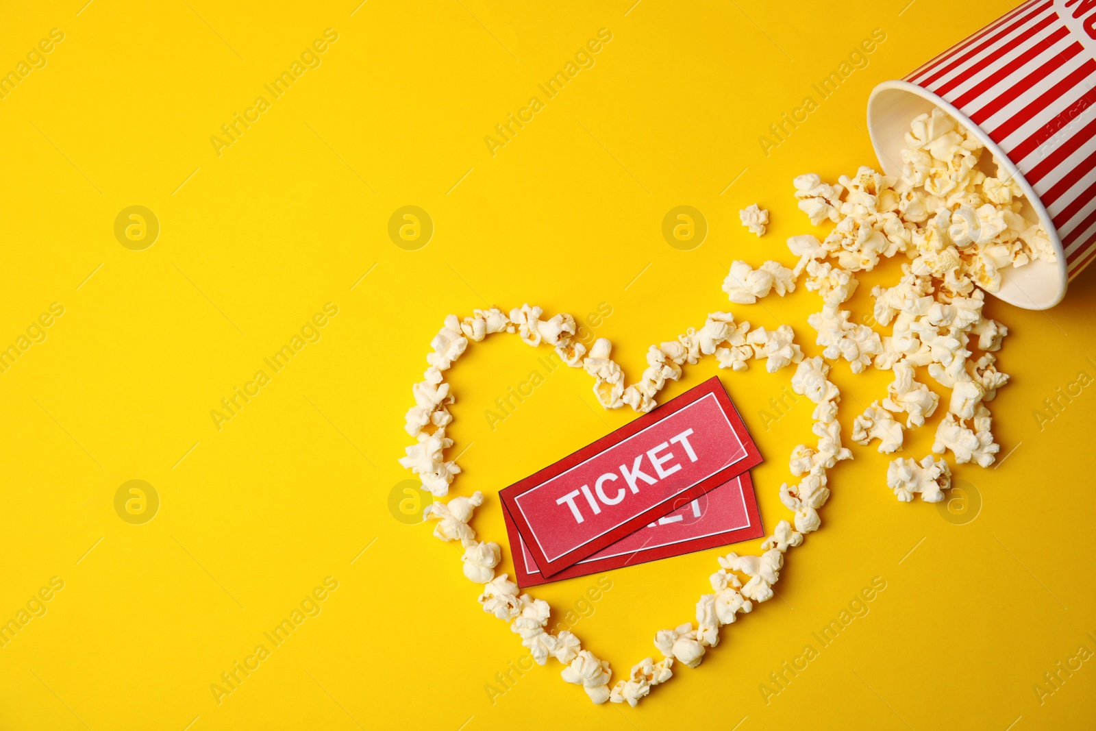 Photo of Cinema tickets and heart made of popcorn on color background, top view. Space for text