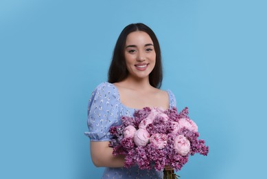 Beautiful woman with bouquet of spring flowers on light blue background