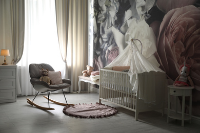 Photo of Baby room interior with stylish crib and floral wallpaper