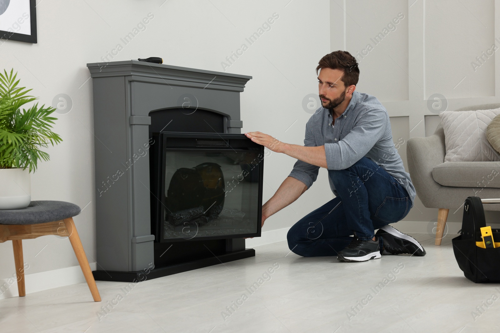 Photo of Man installing electric fireplace near wall in room