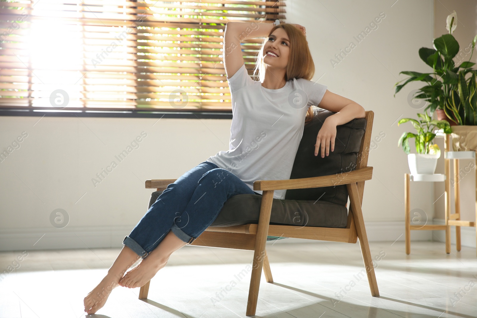 Photo of Young woman relaxing in armchair near window at home