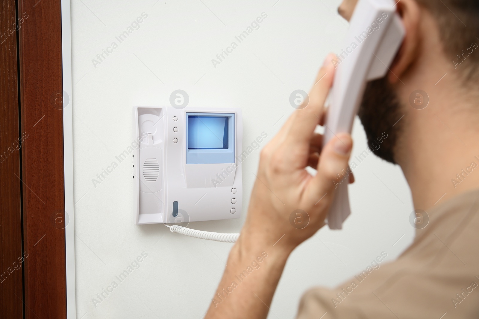 Photo of Man with handset answering intercom call indoors