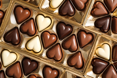 Beautiful heart shaped chocolate candies in box as background, top view