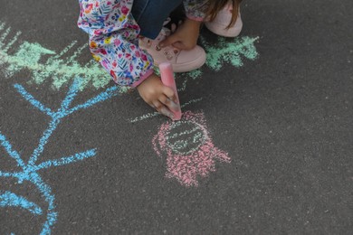 Photo of Child drawing family with chalk on asphalt, closeup