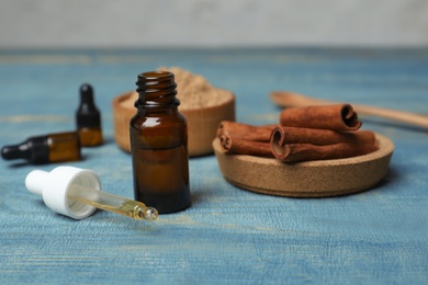 Photo of Bottle with cinnamon oil and sticks on wooden table