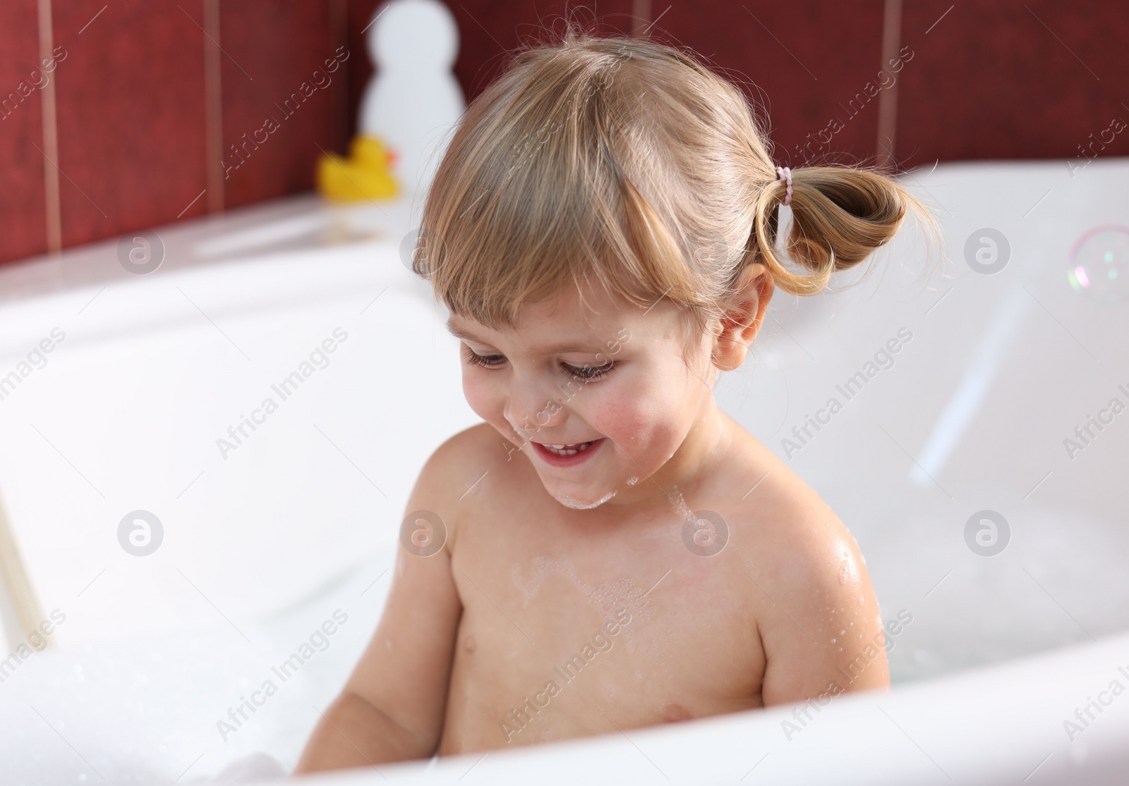 Photo of Little girl bathing in tub at home