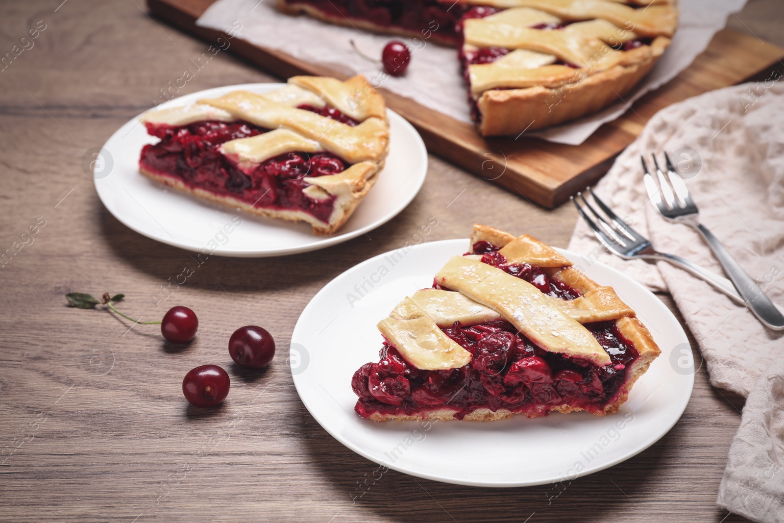 Photo of Slices of delicious fresh cherry pie served on wooden table, closeup