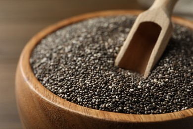 Photo of Wooden bowl with chia seeds and scoop, closeup