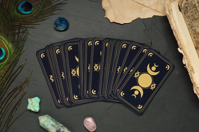 Photo of Tarot cards, peacock feathers, gemstones and old book on black table, flat lay. Reverse side